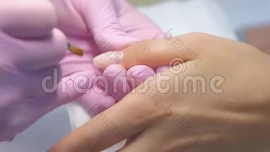 美甲大师是在美容诊所用刷子涂指甲凝胶紫胶。
